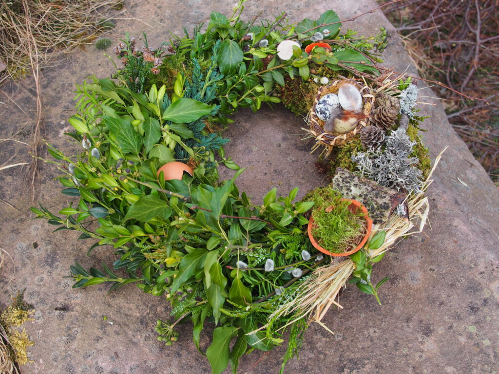 Ein Frühlingskranz liegt auf einem großen Buntsandstein Fels