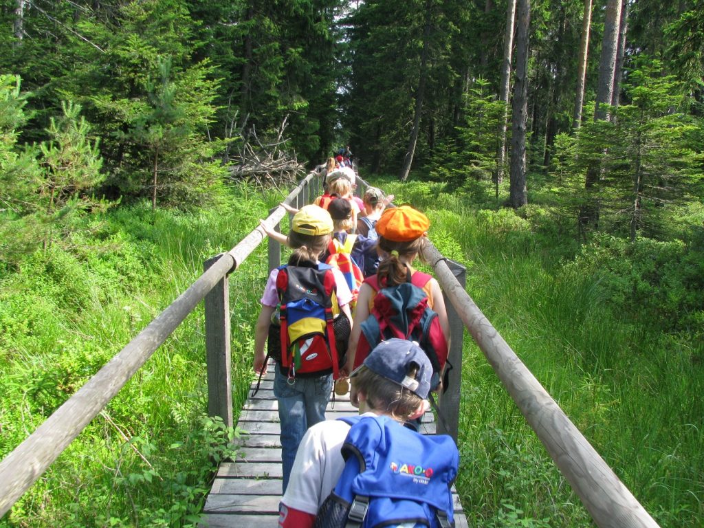Kinder mit Rucksack laufen über den Bohlensteg