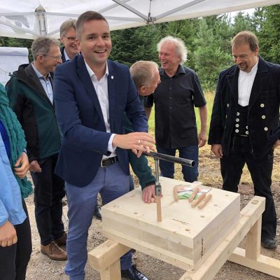 Fröhliche Gruppe, an einem Holzblock mit großen Holzdübeln arbeitend.